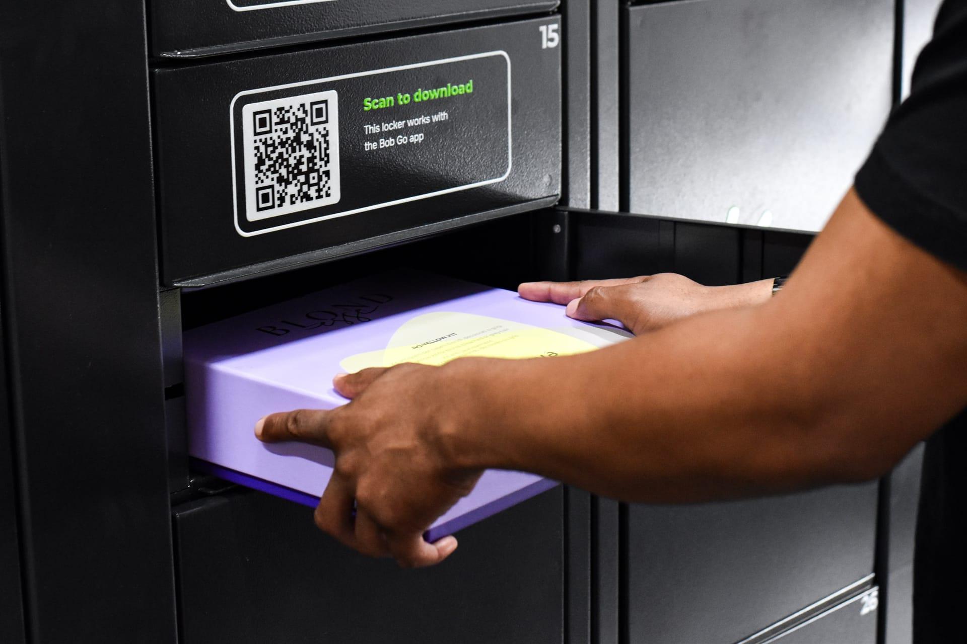 A courier scans the locker QR code and places a parcel into an open compartment.