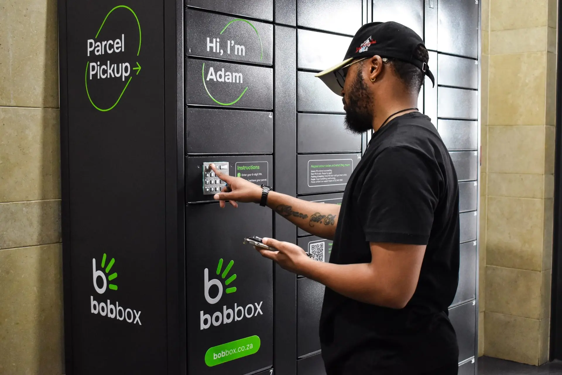 A customer arrives at a Bob Box locker, phone in hand, ready to collect their parcel.